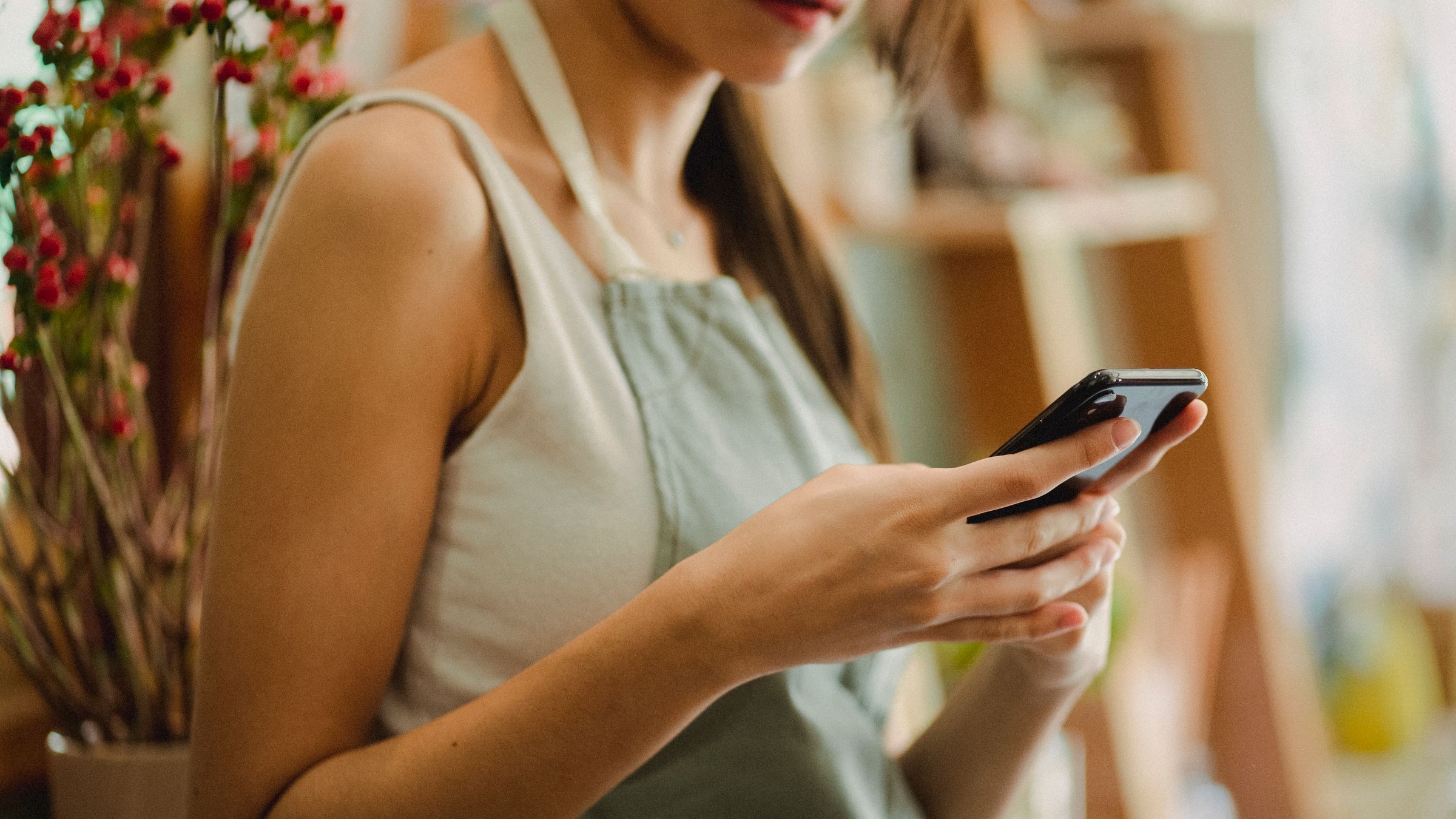Ladeninhaberin schaut auf ihr Smartphone